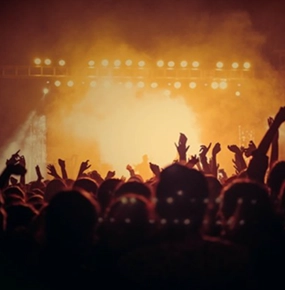 A concert with a full house and enthusiastic fans cheering under bright lights.