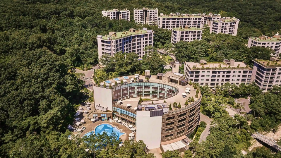 Aerial view of ANTO, a high-end resort set amid forested mountains in South Korea, with modern architecture