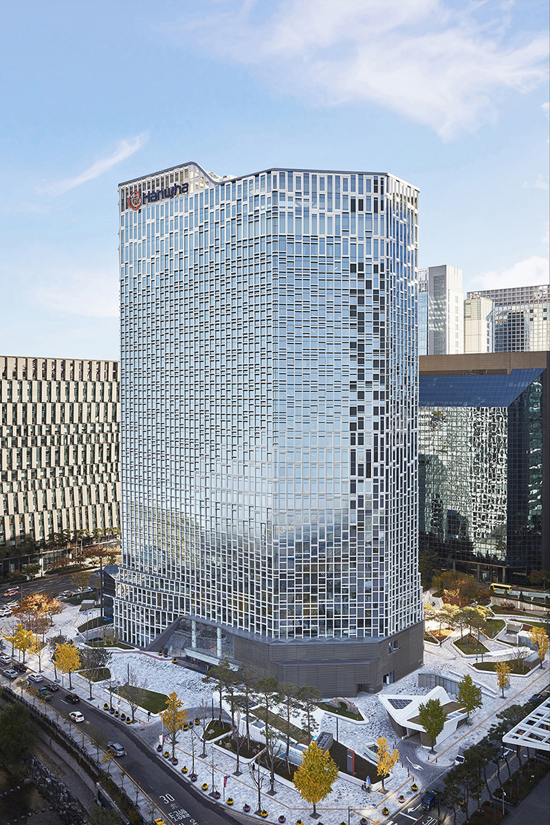 Sunny exterior shot of Hanwha’s Seoul headquarters featuring the gleaming solar PV façade in autumn