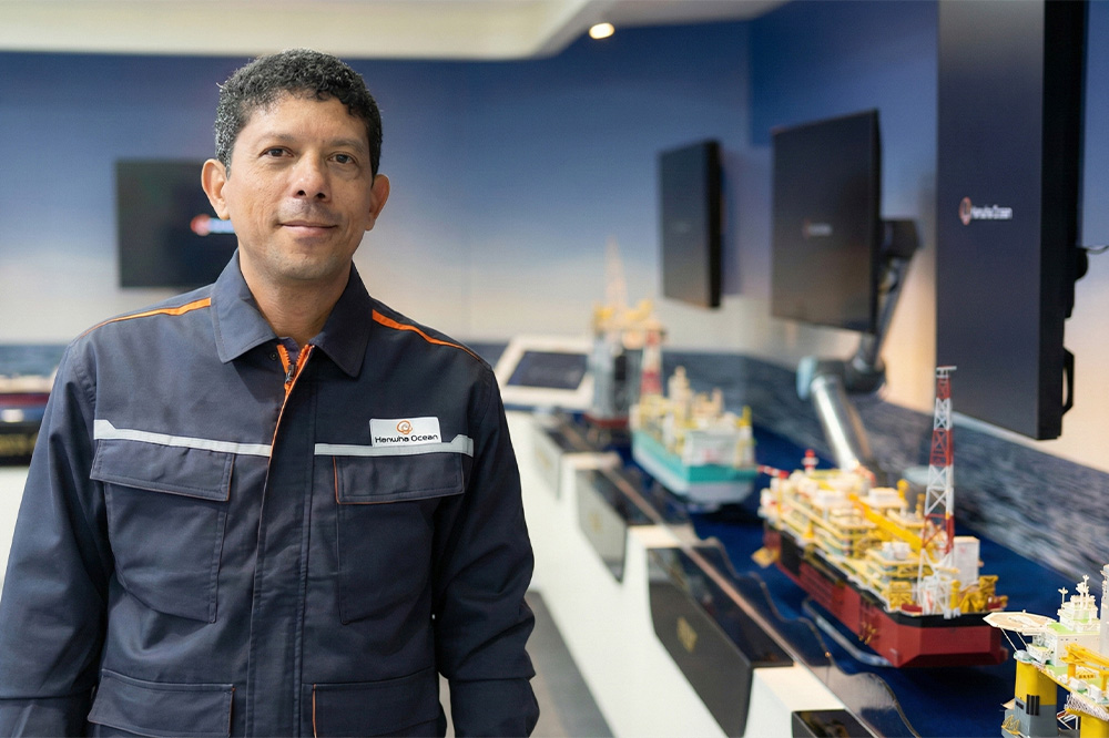 Weverton Nazario, Head of Operations and Maintenance at Hanwha Ocean, standing beside offshore platform models. 