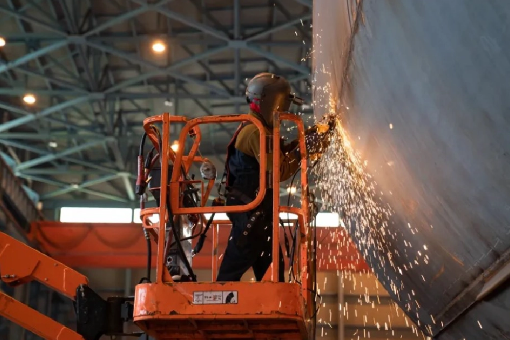 A dual graphic with a man wearing a hard hat looking at plans at Hanwha Philly Shipyard and a man welding on an orange rig.