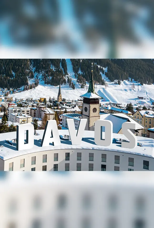 Davos landscape featuring buildings, church towers, and mountains under a clear sky.