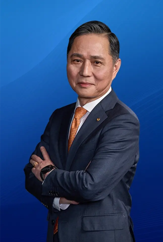 Portrait of Young-chang Shon in a navy suit with folded arms against a blue gradient background.