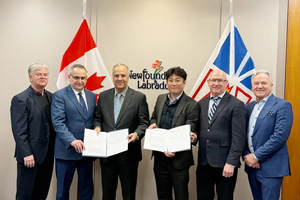 Representatives from Hanwha Ocean and Fermeuse Energy display signed MOU in front of Canadian and Newfoundland & Labrador flags