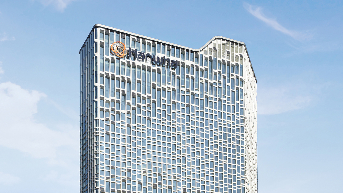 Hanwha’s Seoul headquarters, a skyscraper covered in solar panels, is seen from below on a sunny day. 
