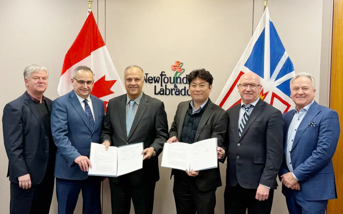 Representatives from Hanwha Ocean and Fermeuse Energy display signed MOU in front of Canadian and Newfoundland & Labrador flags